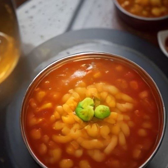 A steel bowl of misal seen from above, next to a glass of chai.